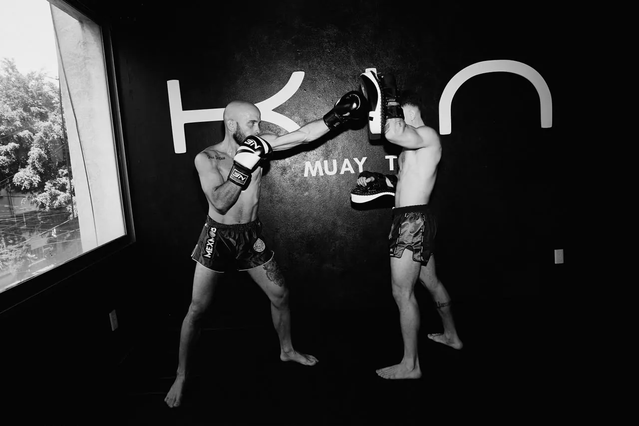 Ricardo sosteniendo los pads a un alumno en KIN Muay Thai, Roma Norte